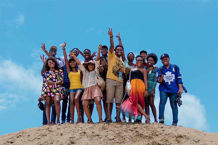 Photos d'un groupe de personnes se tenant sur une dune de sable avec le ciel bleu en toile de fond